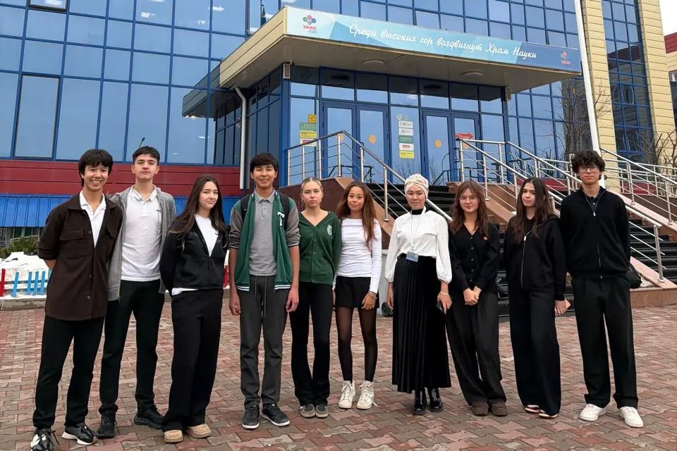 Ten members of the Ayala team standing in a row outside the Tamos Education building in Almaty.